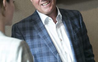 Portrait of Michael Barry wearing a suit and glasses indoors.